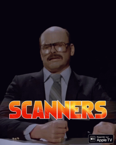 A Man In A Suit And Tie Is Sitting At A Table With The Word Scanners Written In Red Letters GIF