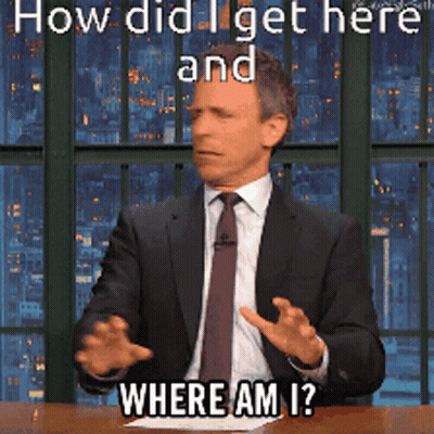 A Man In A Suit And Tie Is Sitting At A Table With The Words How Did I Get Here And Where Am I GIF