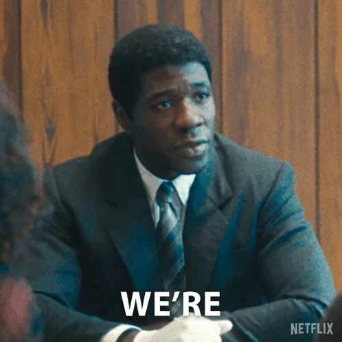A Man In A Suit And Tie Is Sitting At A Table With The Words Investigating Written On The Bottom GIF