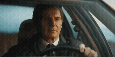 A Man In A Suit And Tie Is Sitting In A Car GIF