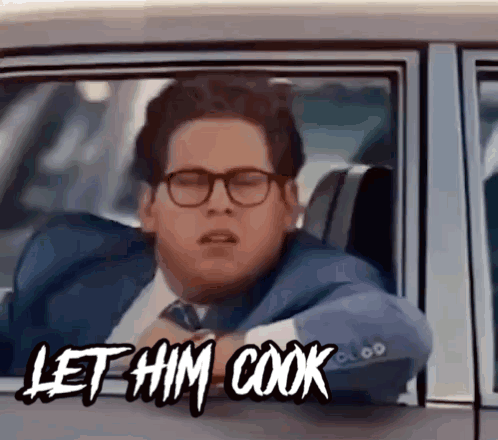 A Man In A Suit And Tie Is Sitting In A Car With The Words Let Him Cook Above Him GIF