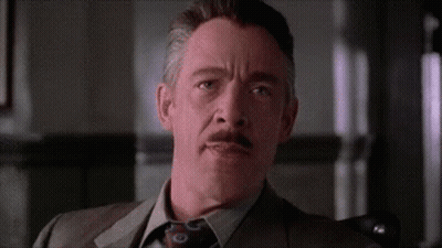 A Man In A Suit And Tie Is Sitting In A Chair . GIF