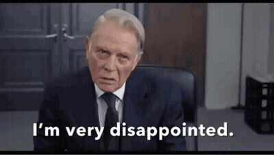 A Man In A Suit And Tie Is Sitting In A Chair . GIF