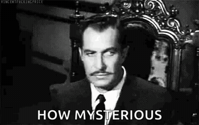 A Man In A Suit And Tie Is Sitting In A Chair And Looking At The Camera . GIF