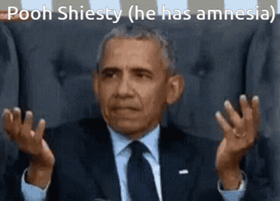 A Man In A Suit And Tie Is Sitting In A Chair And Making A Funny Face With His Hands Outstretched . GIF