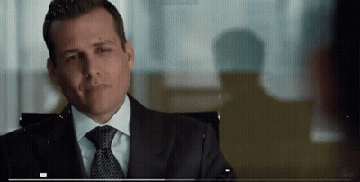 A Man In A Suit And Tie Is Sitting In A Chair And Smiling . GIF