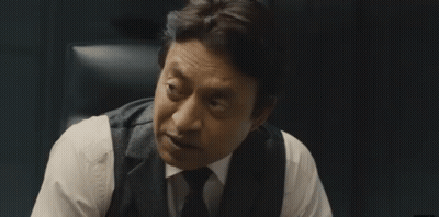 A Man In A Suit And Tie Is Sitting In A Chair And Talking To Someone . GIF