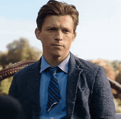A Man In A Suit And Tie Is Sitting In A Chair . GIF