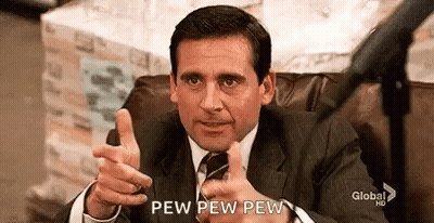 A Man In A Suit And Tie Is Sitting In A Chair Giving A Thumbs Up . GIF
