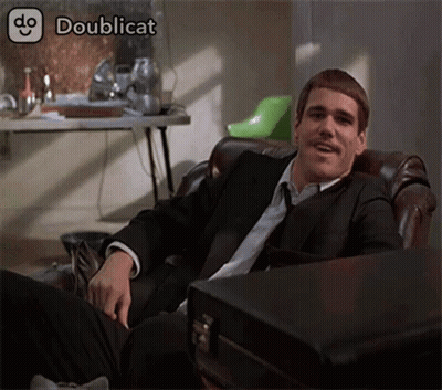 A Man In A Suit And Tie Is Sitting In A Chair With A Briefcase Next To Him .. GIF
