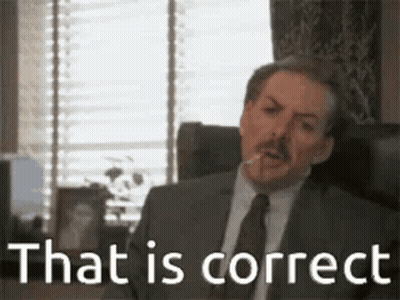 A Man In A Suit And Tie Is Sitting In A Chair With A Cigarette In His Mouth . GIF