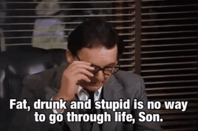 A Man In A Suit And Tie Is Sitting In A Chair With His Eyes Closed And Glasses On . GIF