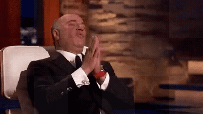 A Man In A Suit And Tie Is Sitting In A Chair With His Eyes Closed And His Hands Folded In Prayer . GIF