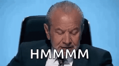 A Man In A Suit And Tie Is Sitting In A Chair With His Eyes Closed And The Words Hmmmm Written On His Face . GIF
