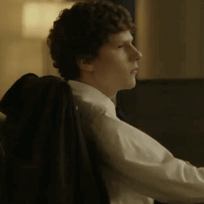 A Man In A Suit And Tie Is Sitting In A Chair With His Jacket On His Back . GIF