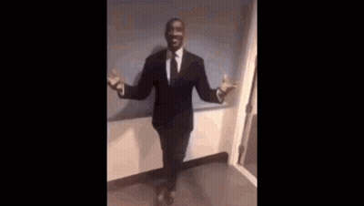 A Man In A Suit And Tie Is Sitting In A Chair With His Legs Crossed . GIF