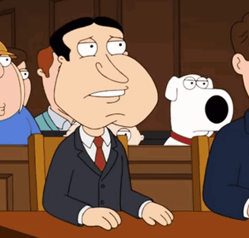 A Man In A Suit And Tie Is Sitting In A Courtroom GIF