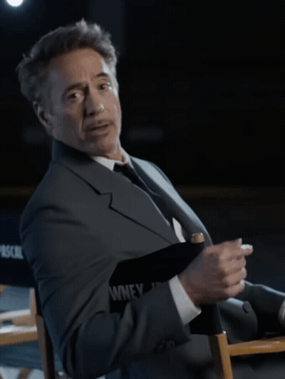 A Man In A Suit And Tie Is Sitting In A Director 'S Chair That Says Pascal On It GIF
