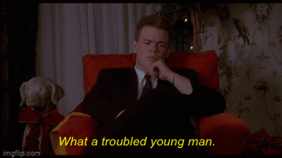 A Man In A Suit And Tie Is Sitting In A Red Chair With The Words What A Troubled Young Man Behind Him GIF