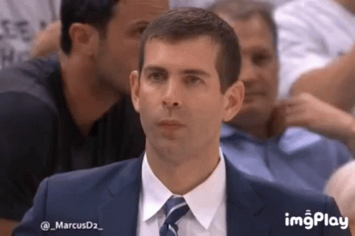 A Man In A Suit And Tie Is Sitting In A Stadium . GIF