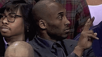 A Man In A Suit And Tie Is Sitting In A Stadium Watching A Basketball Game . GIF