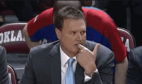 A Man In A Suit And Tie Is Sitting In A Stadium With Oklahoma On The Back Of His Shirt GIF