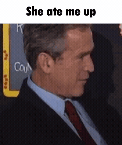 A Man In A Suit And Tie Is Sitting In Front Of A Blackboard That Says She Ate Me Up . GIF