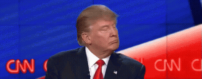 A Man In A Suit And Tie Is Sitting In Front Of A Blue And Red Wall . GIF