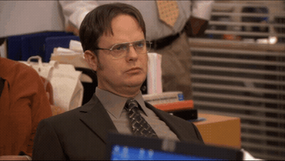A Man In A Suit And Tie Is Sitting In Front Of A Computer GIF