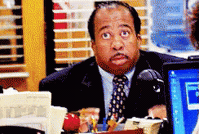 A Man In A Suit And Tie Is Sitting In Front Of A Computer Monitor GIF