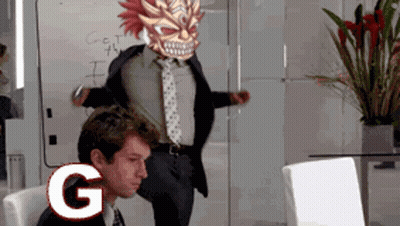 A Man In A Suit And Tie Is Sitting In Front Of A Computer With The Letter G On The Screen GIF