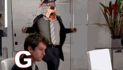 A Man In A Suit And Tie Is Sitting In Front Of A Computer With The Letter G On The Screen GIF