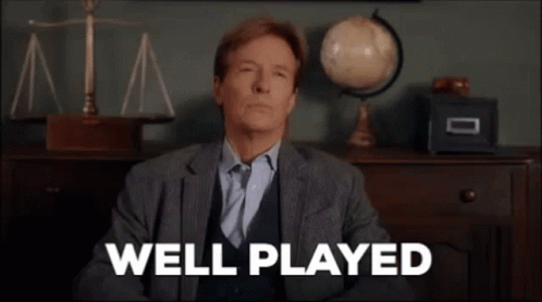 A Man In A Suit And Tie Is Sitting In Front Of A Desk With The Words `` Well Played '' On It . GIF