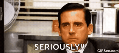 A Man In A Suit And Tie Is Sitting In Front Of A Fan . GIF