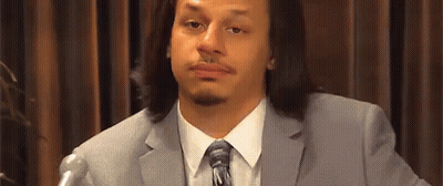 A Man In A Suit And Tie Is Sitting In Front Of A Microphone And Making A Funny Face . GIF