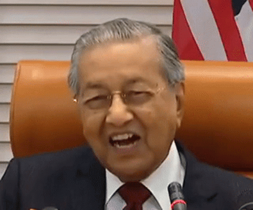 A Man In A Suit And Tie Is Sitting In Front Of A Microphone And Smiling . GIF
