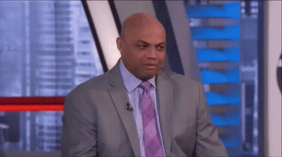 A Man In A Suit And Tie Is Sitting In Front Of A Microphone In A Studio . GIF