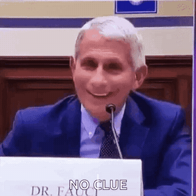 A Man In A Suit And Tie Is Sitting In Front Of A Microphone . GIF