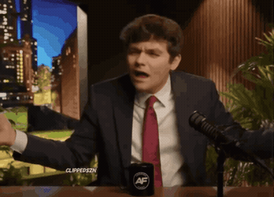 A Man In A Suit And Tie Is Sitting In Front Of A Microphone With A Cup That Says ' Af ' On It GIF
