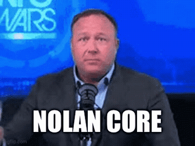 A Man In A Suit And Tie Is Sitting In Front Of A Microphone With The Words Nolan Core On His Face GIF