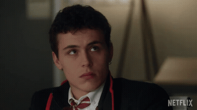 A Man In A Suit And Tie Is Sitting In Front Of A Netflix Sign GIF