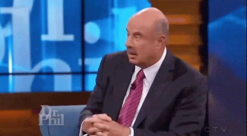A Man In A Suit And Tie Is Sitting In Front Of A Screen That Says Dr Phil On It . GIF