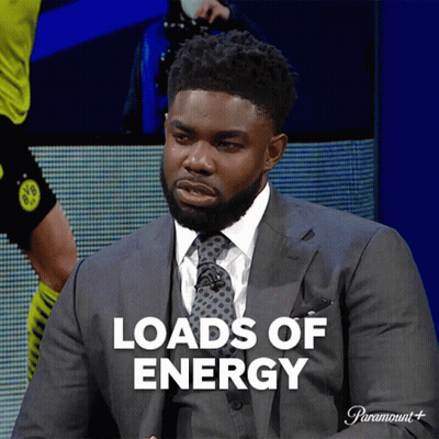 A Man In A Suit And Tie Is Sitting In Front Of A Screen That Says Loads Of Energy GIF