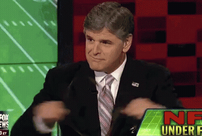 A Man In A Suit And Tie Is Sitting In Front Of A Screen That Says Nf Under F GIF