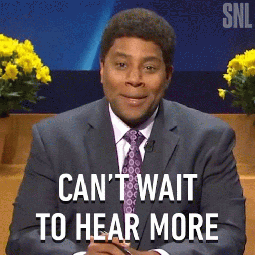 A Man In A Suit And Tie Is Sitting In Front Of A Sign That Says Can 'T Wait To Hear More GIF