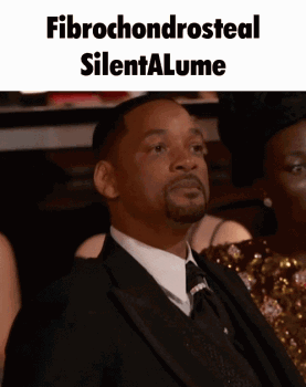 A Man In A Suit And Tie Is Sitting In Front Of A Sign That Says Fibrochondrosteal Silentalume GIF