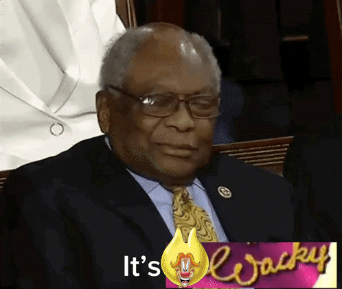 A Man In A Suit And Tie Is Sitting In Front Of A Sign That Says " It 'S Wacky " GIF
