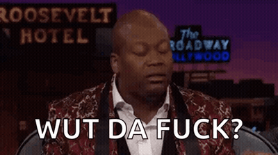 A Man In A Suit And Tie Is Sitting In Front Of A Sign That Says The Roosevelt Hotel . GIF