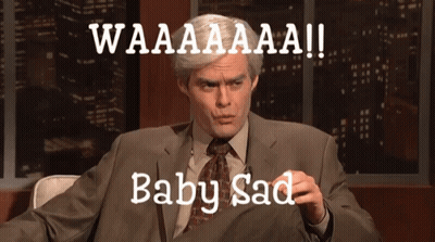 A Man In A Suit And Tie Is Sitting In Front Of A Sign That Says Waaaaaaa Baby Sad GIF