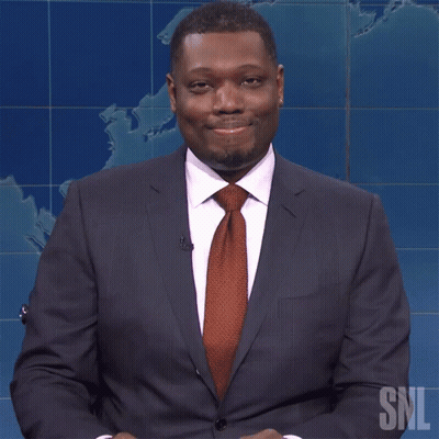 A Man In A Suit And Tie Is Sitting In Front Of A Snl Logo GIF